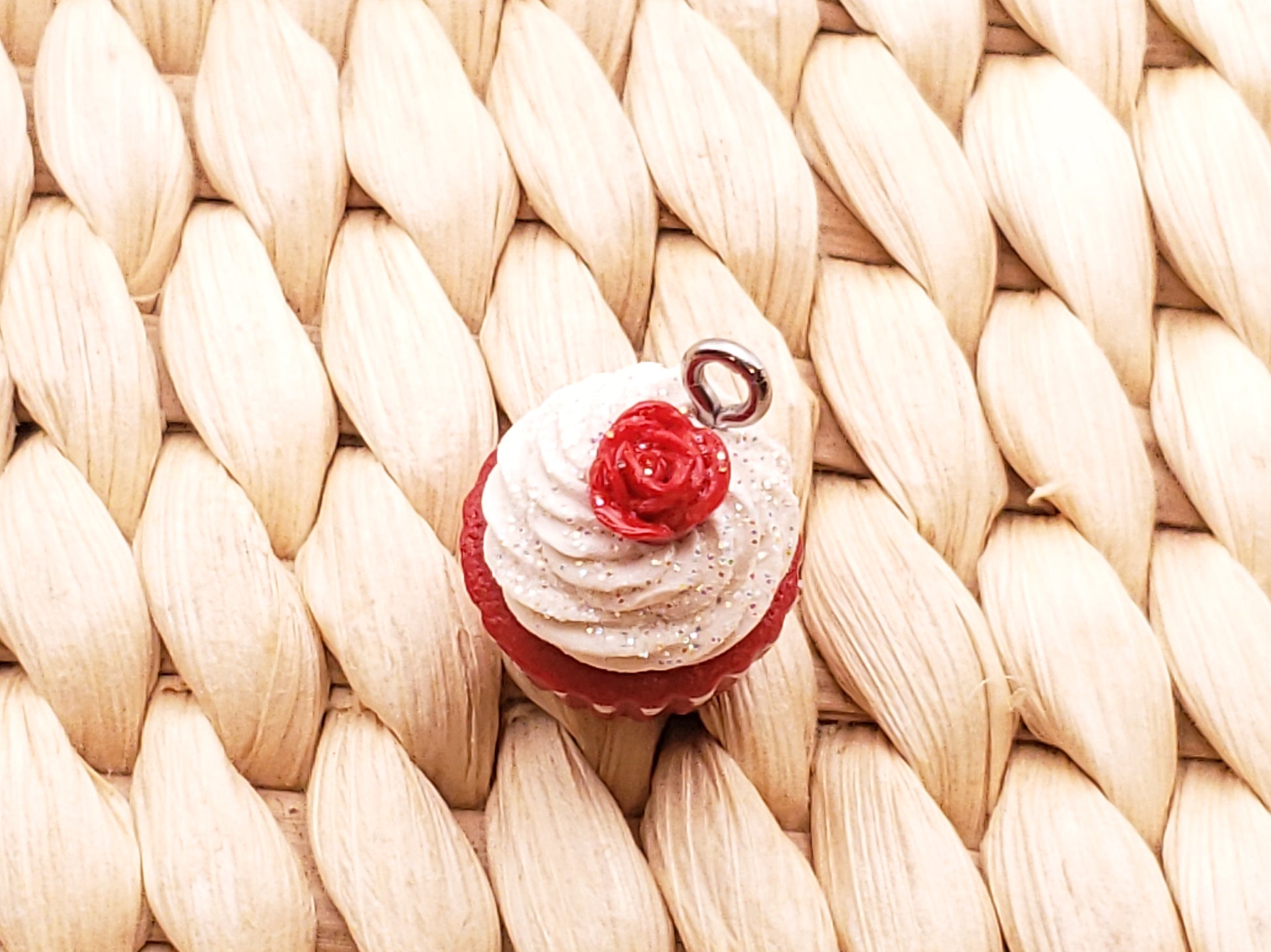 a cupcake with white frosting and a red rose on top