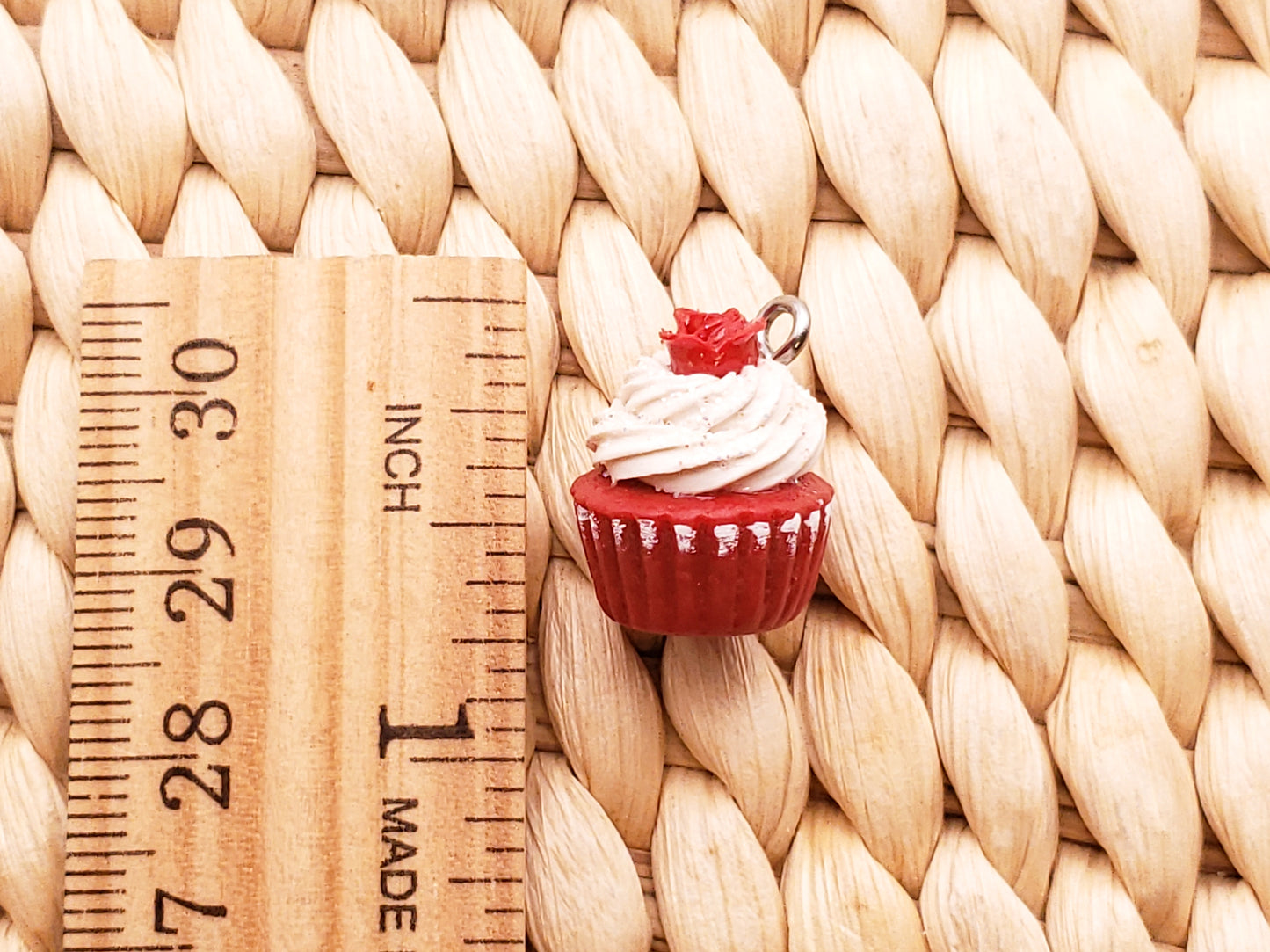 a red cupcake with white frosting sitting on a wooden ruler